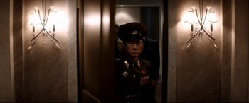 Movie still from “The Interview” (2014), directed by Evan Goldberg – A man in a military uniform standing next to a door; Medium shot, Over the shoulder angle