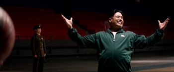 Movie still from “The Interview” (2014), directed by Evan Goldberg – A man in a green jacket holding his arms out; Medium shot, Low angle