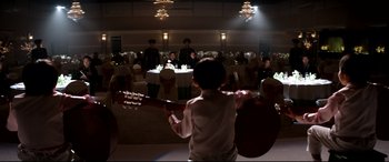 Movie still from “The Interview” (2014), directed by Evan Goldberg – A young boy holding a guitar in front of a group of people; Wide shot, Over the shoulder angle