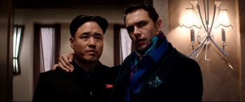 Movie still from “The Interview” (2014), directed by Evan Goldberg – Two men posing for a picture in a room; Medium shot, Low angle