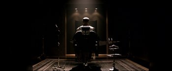 Movie still from “The Interview” (2014), directed by Evan Goldberg – A man sitting in a chair in front of a microphone; Medium shot, Low angle