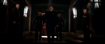 Movie still from “The Interview” (2014), directed by Evan Goldberg – A man in a black suit standing next to two other men; Medium shot, Low angle