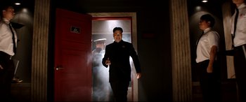 Movie still from “The Interview” (2014), directed by Evan Goldberg – A man in a black suit walking through a door way; Medium shot, Low angle