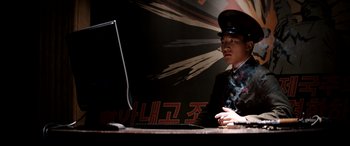 Movie still from “The Interview” (2014), directed by Evan Goldberg – A man sitting at a table in front of a computer; Medium shot, Low angle