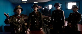 Movie still from “The Interview” (2014), directed by Evan Goldberg – A group of men standing around a wooden table; Medium shot, Over the shoulder angle