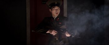 Movie still from “The Interview” (2014), directed by Evan Goldberg – A man in a uniform holding a gun in front of a wall; Medium shot, Low angle