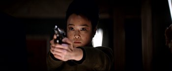 Movie still from “The Interview” (2014), directed by Evan Goldberg – A young person holding a gun in a dark room; Close Up shot, Over the shoulder angle