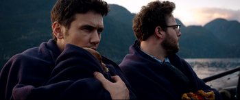 Movie still from “The Interview” (2014), directed by Evan Goldberg – Two men wrapped in a blanket looking at the camera; Close Up shot, High angle