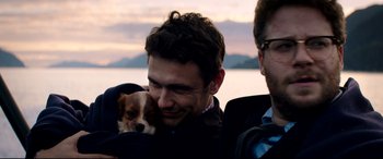 Movie still from “The Interview” (2014), directed by Evan Goldberg – A man holding a dog in his arms while another man looks on; Close Up shot, High angle