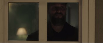 Movie still from “The Invisible Guest” (2016), directed by Oriol Paulo – A man with a beard looking out of a window; Close Up shot, Low angle