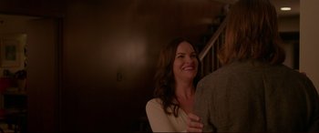 Movie still from “The Invitation” (2015), directed by Karyn Kusama – A woman smiling while standing next to a man in front of a staircase; Medium shot, Over the shoulder angle