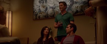 Movie still from “The Invitation” (2015), directed by Karyn Kusama – A man holding a wine glass in front of two other people; Medium shot, Over the shoulder angle