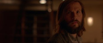 Movie still from “The Invitation” (2015), directed by Karyn Kusama – A man with long hair and a goatee is looking at the camera; Close Up shot, Over the shoulder angle