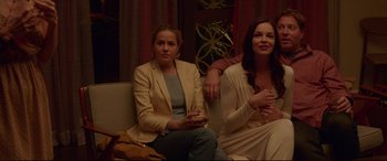 Movie still from “The Invitation” (2015), directed by Karyn Kusama – Two women are sitting on a couch and one of them is holding a cell phone; Medium shot, High angle