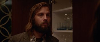 Movie still from “The Invitation” (2015), directed by Karyn Kusama – A man with long hair and a goatee looking to his left; Close Up shot, Over the shoulder angle