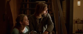 Movie still from “The Invitation” (2015), directed by Karyn Kusama – A man and a girl sitting next to each other in a library; Medium shot, Over the shoulder angle