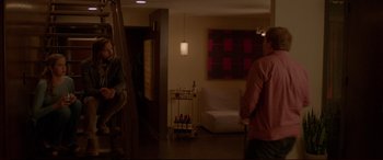Movie still from “The Invitation” (2015), directed by Karyn Kusama – Two people in a living room with a white couch; Wide shot, Over the shoulder angle