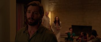 Movie still from “The Invitation” (2015), directed by Karyn Kusama – A group of people standing in a room with a man; Medium shot, Over the shoulder angle