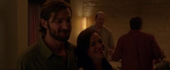 Movie still from “The Invitation” (2015), directed by Karyn Kusama – A man and a woman smile at a party; Close Up shot, Over the shoulder angle