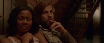 Movie still from “The Invitation” (2015), directed by Karyn Kusama – A man sitting next to a woman in a room; Medium shot, Over the shoulder angle