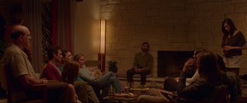 Movie still from “The Invitation” (2015), directed by Karyn Kusama – A group of people sitting in a living room next to a fire place; Wide shot, Over the shoulder angle