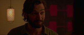 Movie still from “The Invitation” (2015), directed by Karyn Kusama – A person with long hair and a beard; Close Up shot, Over the shoulder angle