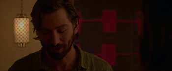 Movie still from “The Invitation” (2015), directed by Karyn Kusama – A man with long hair and a goatee is smiling; Close Up shot, Over the shoulder angle