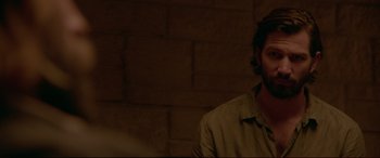 Movie still from “The Invitation” (2015), directed by Karyn Kusama – A man with a beard is standing in front of a brick wall; Close Up shot, Over the shoulder angle