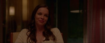 Movie still from “The Invitation” (2015), directed by Karyn Kusama – A woman sitting at a table with a smile on her face; Close Up shot, Over the shoulder angle
