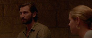 Movie still from “The Invitation” (2015), directed by Karyn Kusama – A man with long hair and a beard wearing a brown shirt; Close Up shot, Over the shoulder angle