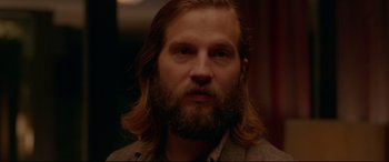 Movie still from “The Invitation” (2015), directed by Karyn Kusama – A person with long hair and a beard; Close Up shot, Over the shoulder angle