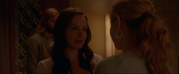 Movie still from “The Invitation” (2015), directed by Karyn Kusama – Two women are standing in a room and one of them is smiling at the camera; Close Up shot, Over the shoulder angle