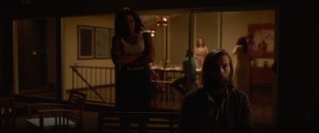 Movie still from “The Invitation” (2015), directed by Karyn Kusama – A woman sitting on top of a bench next to a man; Wide shot, Over the shoulder angle