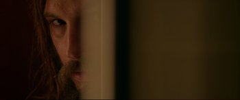 Movie still from “The Invitation” (2015), directed by Karyn Kusama – A man with a beard is looking out of a window; Extreme Close Up shot, Over the shoulder angle