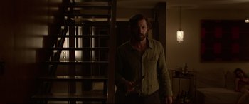 Movie still from “The Invitation” (2015), directed by Karyn Kusama – A man standing in a dark room holding a knife; Medium shot, Low angle