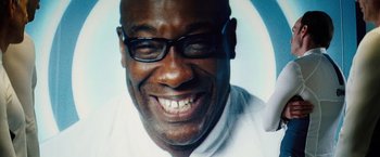 Movie still from “The Island” (2005), directed by Michael Bay – A person wearing glasses and smiling; Close Up shot, Overhead angle