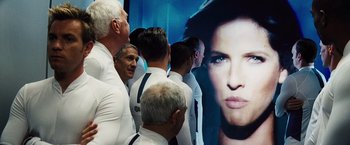 Movie still from “The Island” (2005), directed by Michael Bay – A group of men standing next to each other in front of a poster; Medium shot, Over the shoulder angle