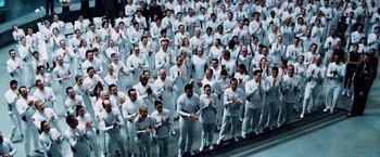 Movie still from “The Island” (2005), directed by Michael Bay – A large group of people standing in a room together; Wide shot, High angle