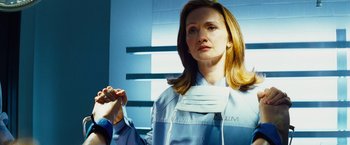 Movie still from “The Island” (2005), directed by Michael Bay – A woman in a blue lab coat holding a pair of gloves; Close Up shot, Over the shoulder angle