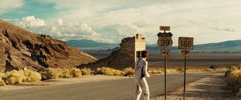 Movie still from “The Island” (2005), directed by Michael Bay – A man in white standing on the side of a road; Extreme Wide shot, Over the shoulder angle