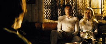 Movie still from “The Island” (2005), directed by Michael Bay – A man sitting on top of a brown leather couch; Medium shot, Low angle