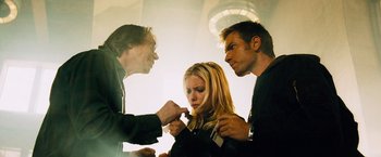 Movie still from “The Island” (2005), directed by Michael Bay – A woman getting her hair cut by two men; Medium shot, Low angle
