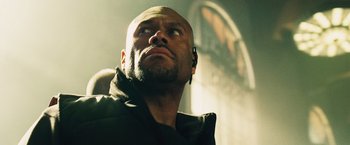 Movie still from “The Island” (2005), directed by Michael Bay – A bald man with a beard looking upward; Close Up shot, Low angle