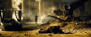 Movie still from “The Island” (2005), directed by Michael Bay – A man laying on the ground next to an angel statue; Wide shot, Low angle