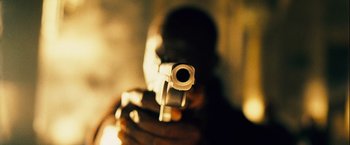Movie still from “The Island” (2005), directed by Michael Bay – A man is holding a gun in front of his face; Extreme Close Up shot, Low angle