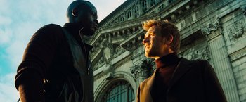 Movie still from “The Island” (2005), directed by Michael Bay – Two men standing next to each other in front of a building; Medium shot, Low angle