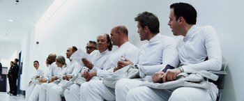 Movie still from “The Island” (2005), directed by Michael Bay – A group of men sitting in a row on a bench; Medium shot, Low angle