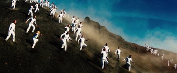 Movie still from “The Island” (2005), directed by Michael Bay – A group of men in white suits running up a hill; Extreme Wide shot, Overhead angle