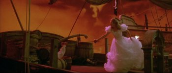 Movie still from “The Jewel of the Nile” (1985), directed by Lewis Teague – A woman in a white dress is holding a sword; Wide shot, High angle