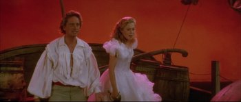 Movie still from “The Jewel of the Nile” (1985), directed by Lewis Teague – A man and a woman in a white dress; Medium shot, Low angle